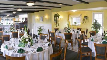 A restaurant with multiple round tables set for dining, featuring white tablecloths and green napkins.