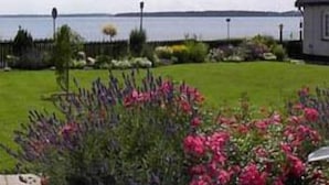 A garden with a variety of flowers and a view of the sea. - Hotel Fjordkroen (Tappernoje)