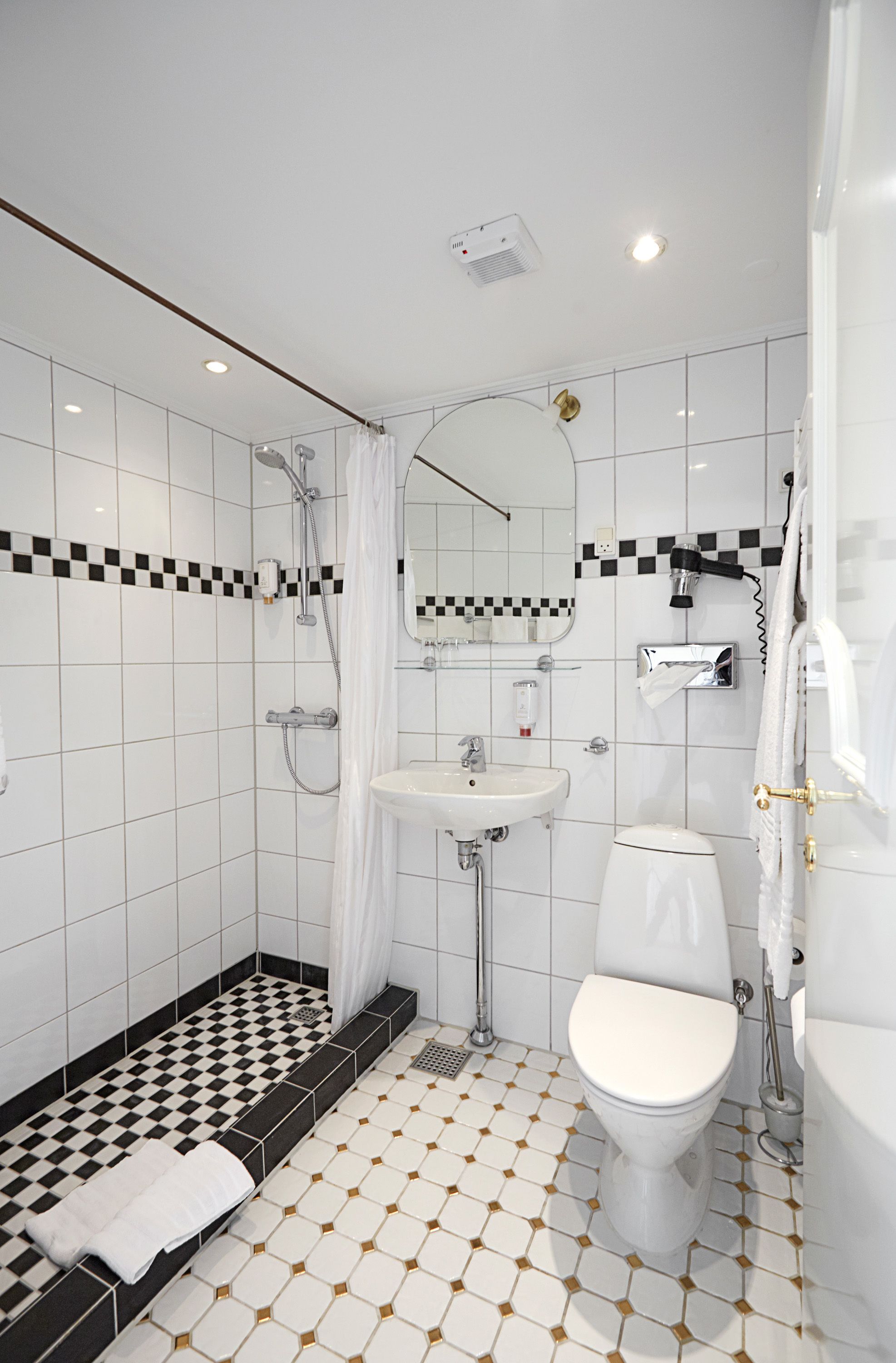 A modern bathroom with a checkered floor pattern, a white sink, a toilet, and a shower area.