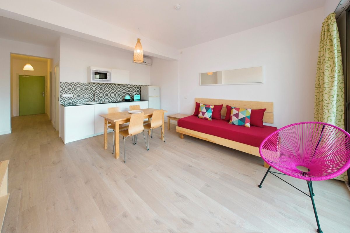 Een moderne woonkamer met een bank, een eettafel en een kleurrijke stoel.