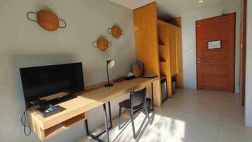 A compact room with a wooden desk, a television, and a chair.