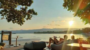 Um deck com vista para um lago e montanhas, uma placa com a frase 'a jornada' e uma pessoa relaxando.