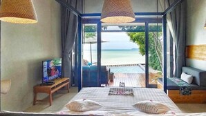 A hotel room with a bed, a TV, and a view of the beach and pool. - Casa De Mar (Koh Samui)