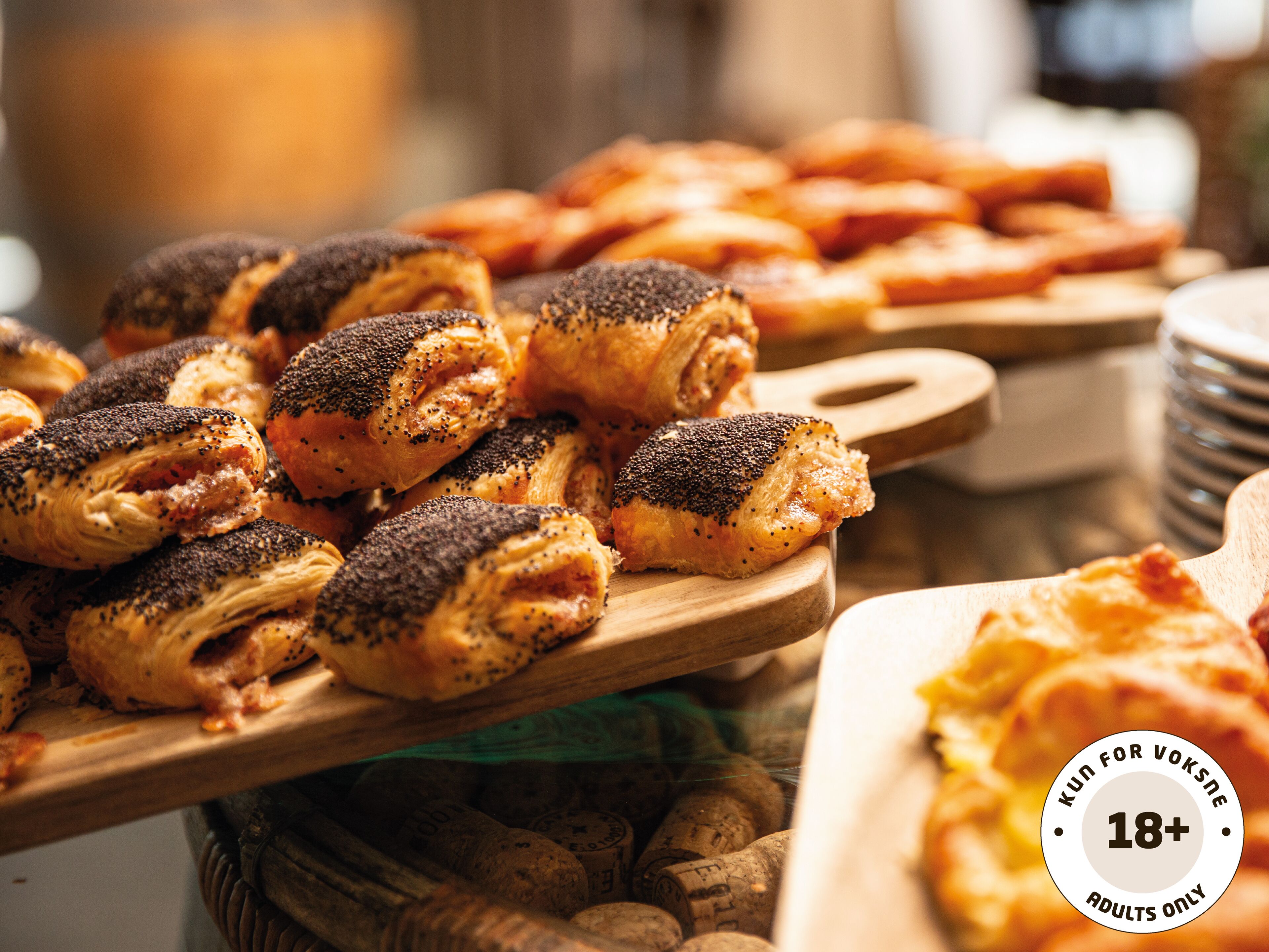 Verschiedene Backwaren auf Holzbrettern, darunter Mohnbrötchen und andere Gebäckstücke.