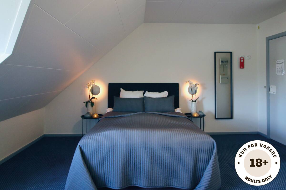 Een slaapkamer met een bed, nachtkastjes en wandlampen.