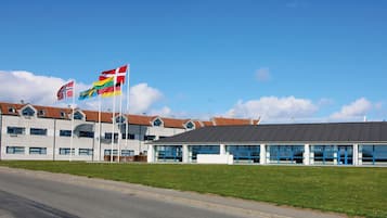 Een gebouw met diverse vlaggen, waaronder de Noorse vlag, en een bordje met de tekst 'alleen volwassenen'.