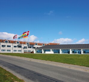 Un edificio con varias banderas, incluyendo la noruega, y un cartel que indica que es solo para adultos.