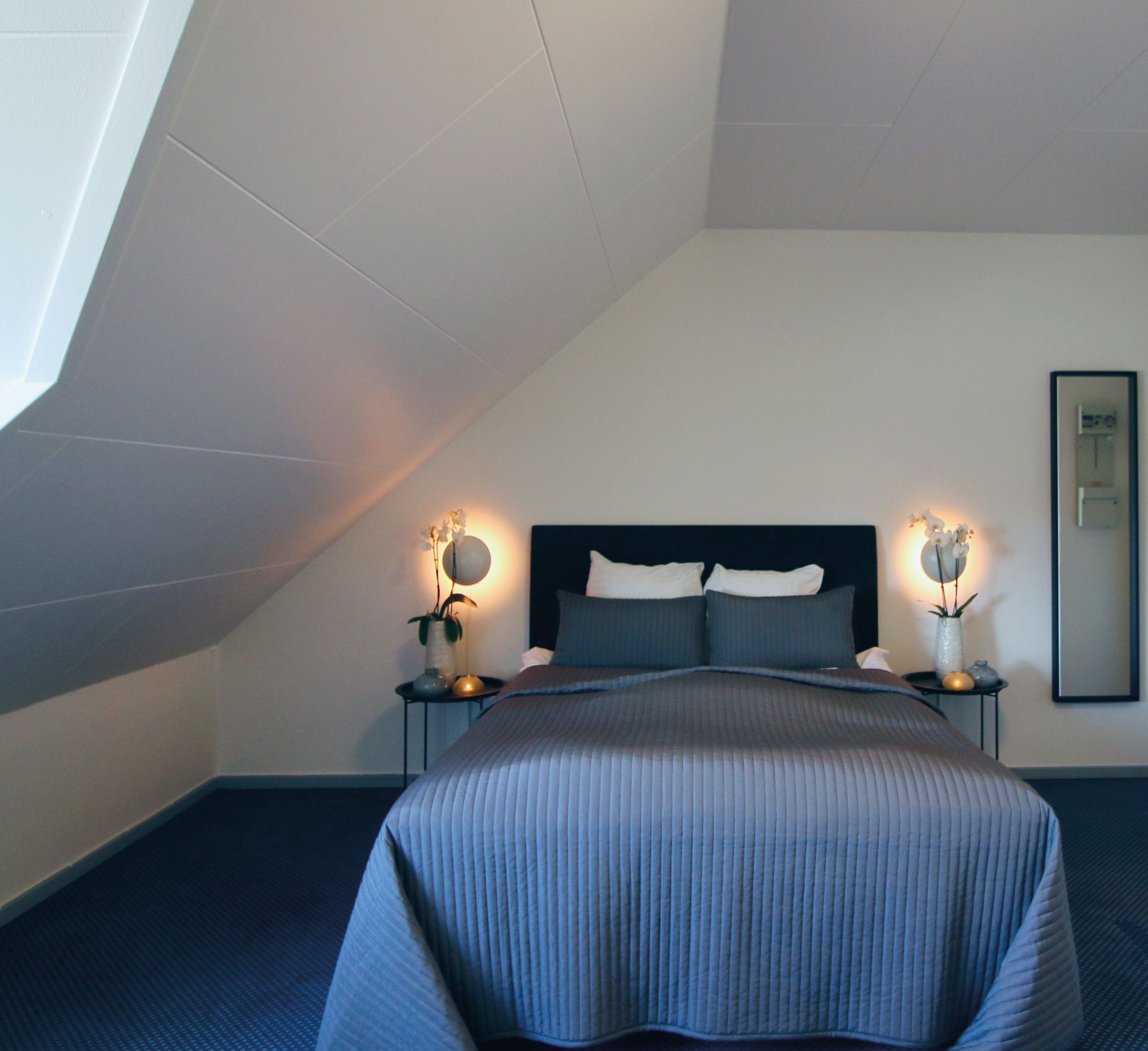 A bedroom with a bed, bedside tables, and wall-mounted lamps.