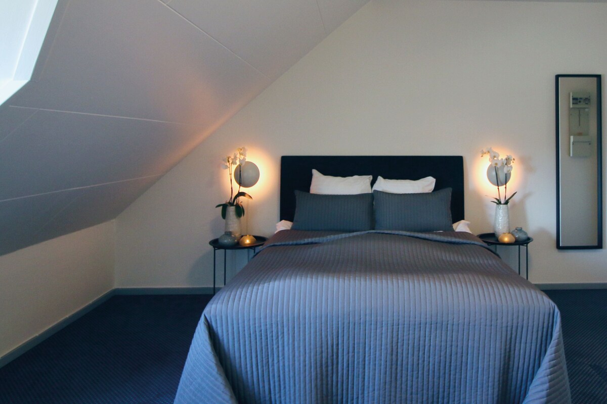 Un dormitorio con cama, mesitas de noche y lámparas de pared.