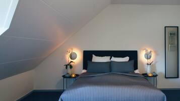 A bedroom with a bed, bedside tables, and wall-mounted lamps.