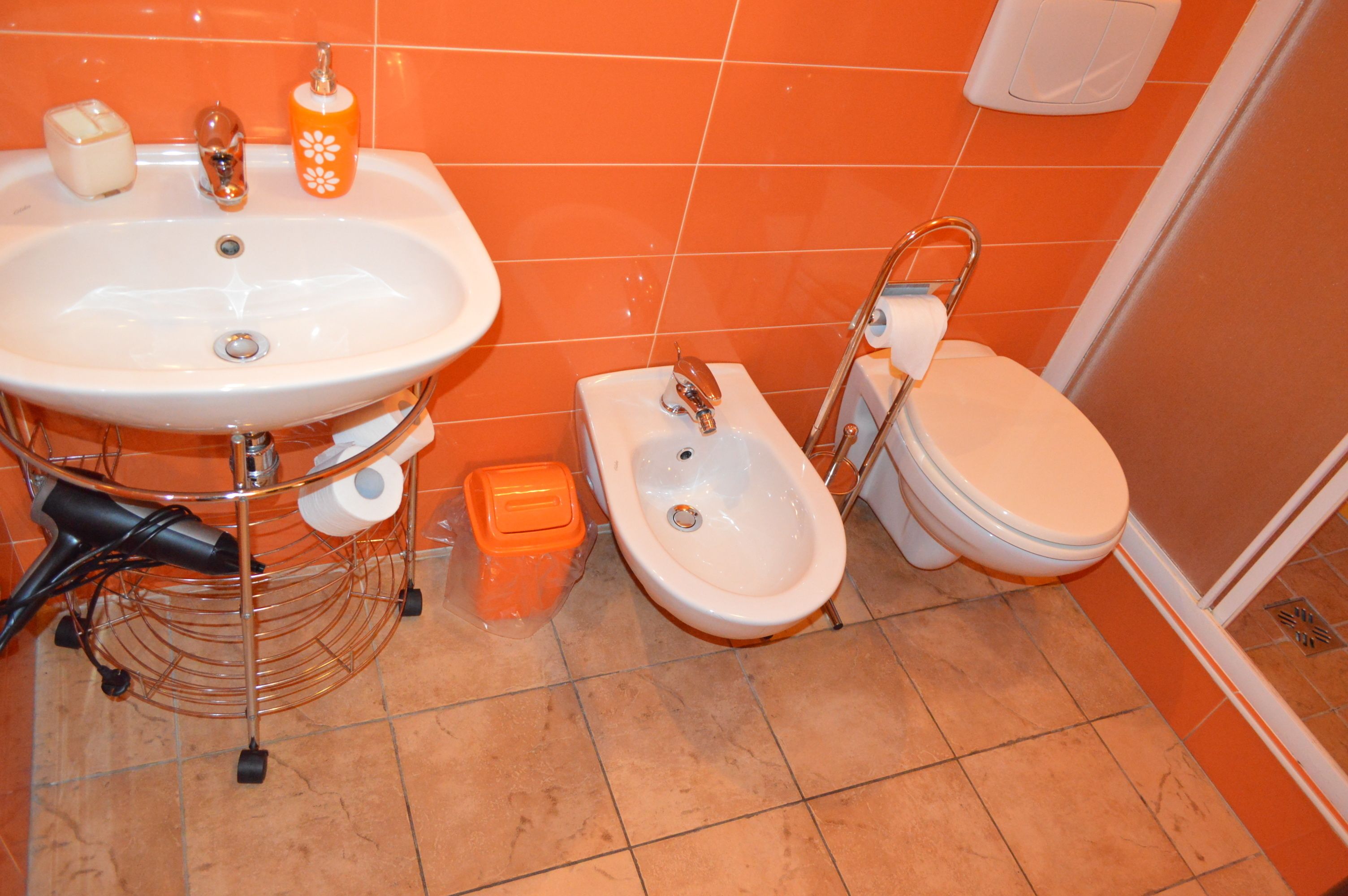 Une salle de bain équipée d’un lavabo, d’un bidet, de toilettes et d’un sèche-cheveux posé sur un support.