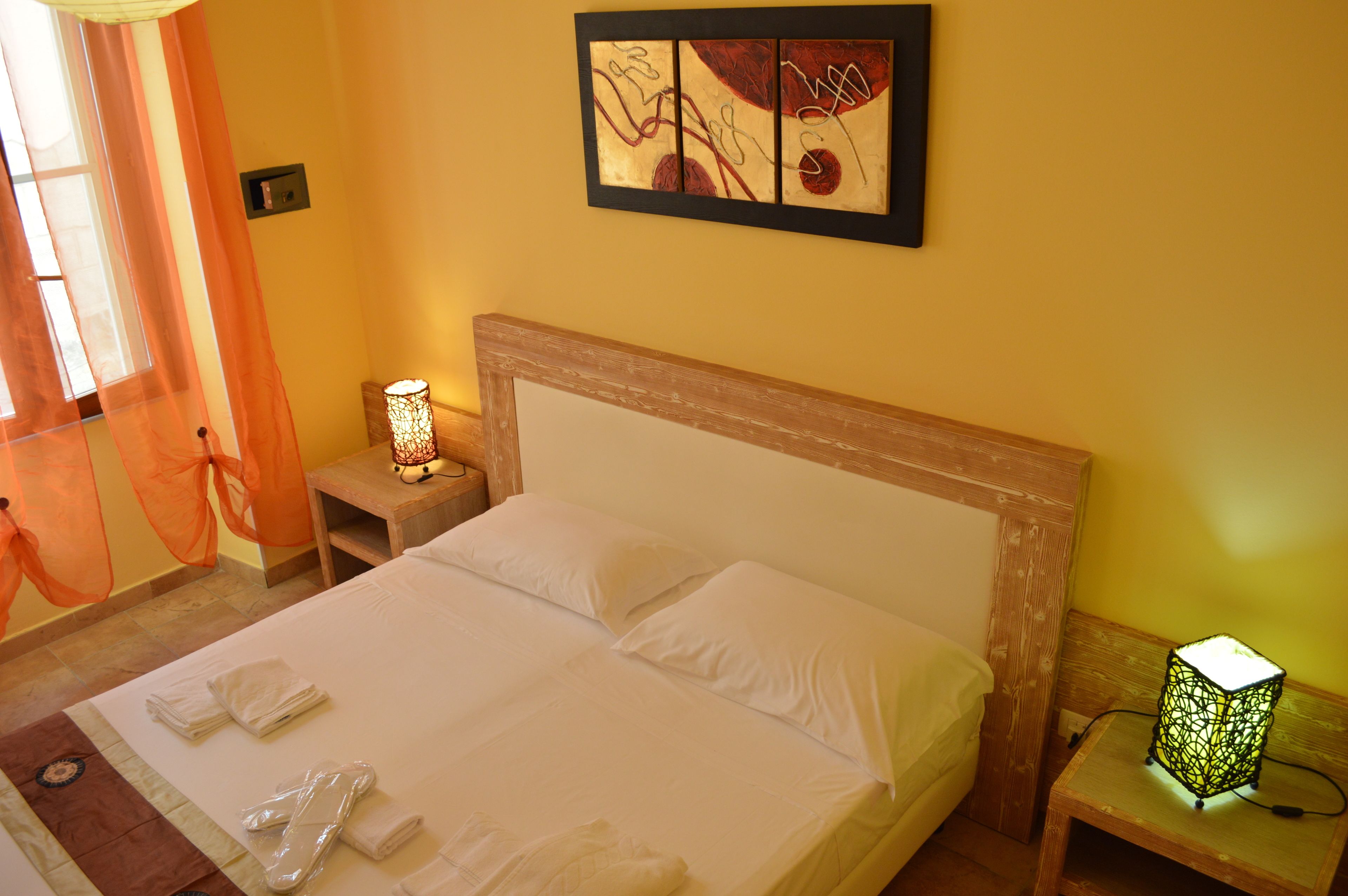 A neatly made bed with white linens, a bedside table with a lamp, and a wall art piece above the bed.