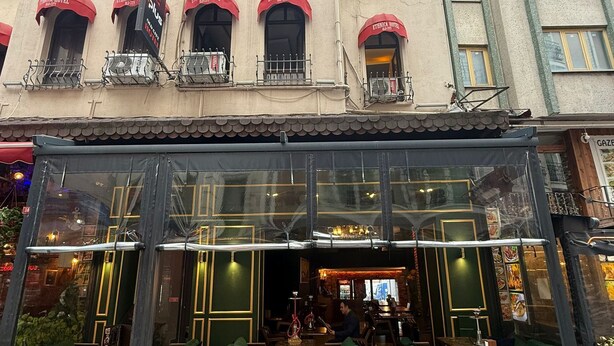Un immeuble doté de nombreux balcons, un magasin avec une façade en verre et des places assises à l’extérieur.