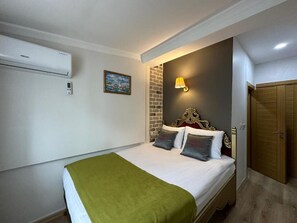 Ein Hotelzimmer mit Bett, Wandklimaanlage, Bild, Lampe und Tür.
