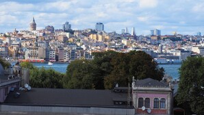 Une vue urbaine mettant en scène une tour historique imposante, des bâtiments urbains denses et une étendue d’eau au premier plan.