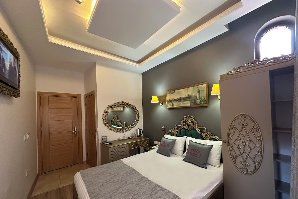 A bedroom with a bed, a dresser, a mirror, a painting, and a ceiling light fixture.