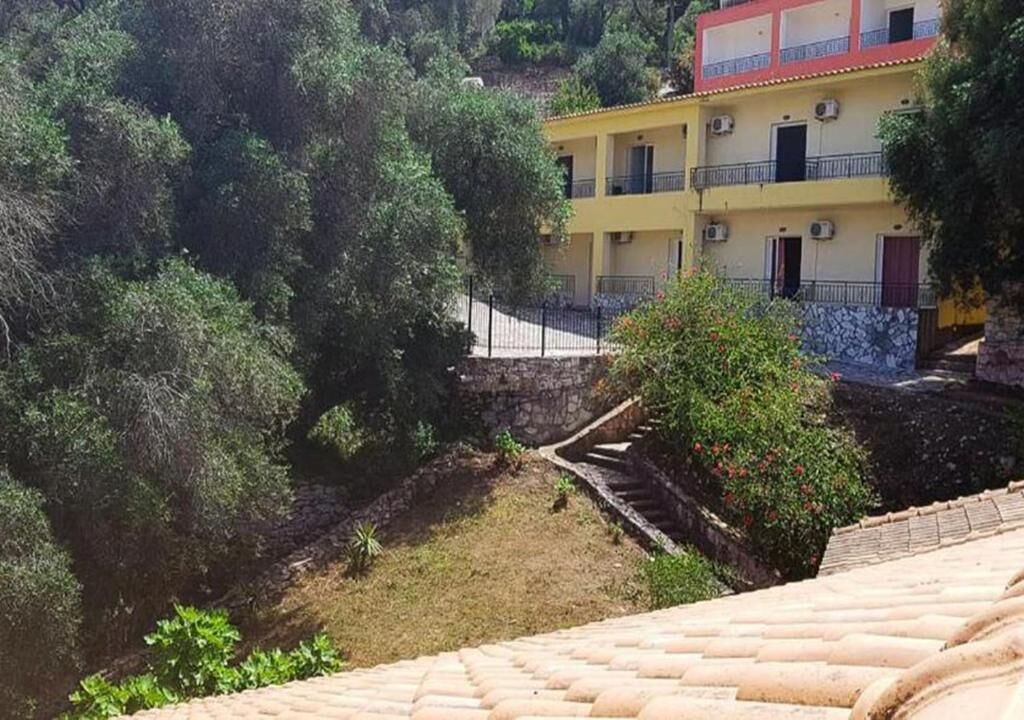 Ein Gebäude mit einer gelben Fassade, mehreren Balkonen und einer Steintreppe, die zu einer unteren Ebene führt.
