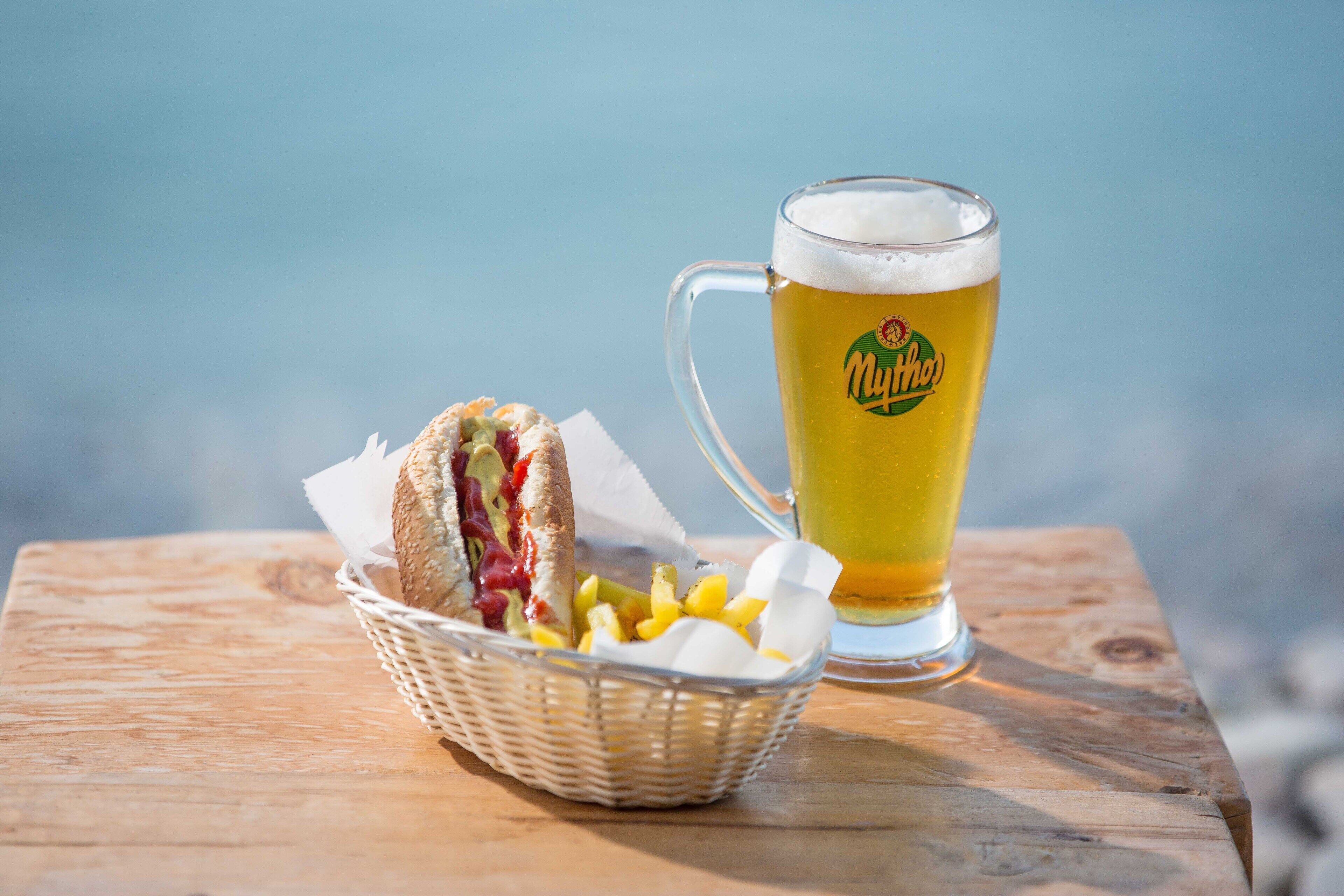 A wooden table with a basket of food and a glass of beer.