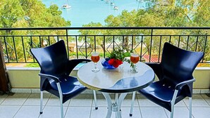 A balcony with two chairs, a table, and two glasses of drink. - Amfitriti Hotel (Paxos)