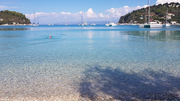 A clear coastal area with boats and a rocky shoreline. - Amfitriti Hotel (Paxos)