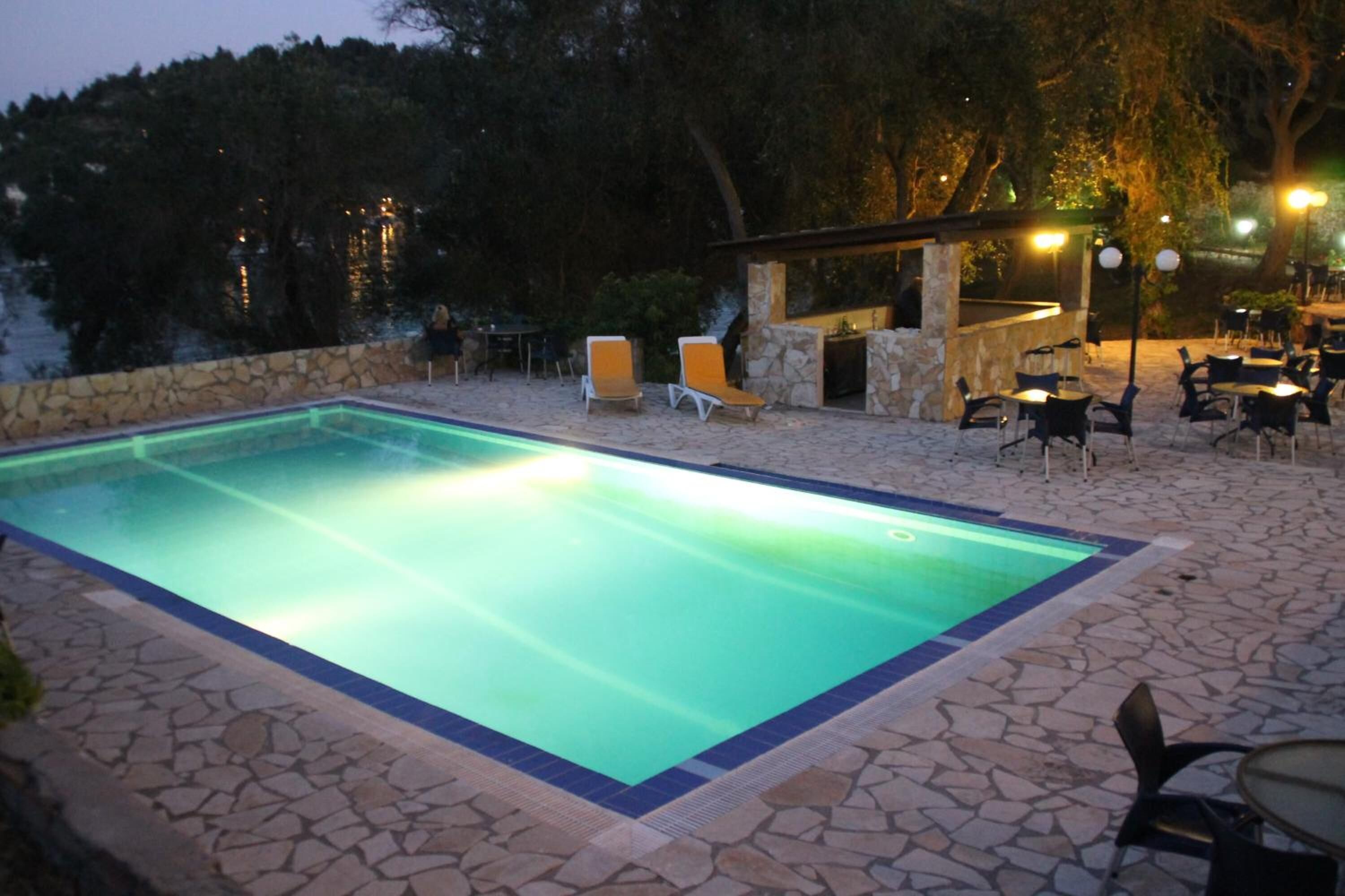 A swimming pool with stone tiles, outdoor seating, and a stone wall.