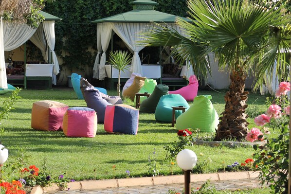 A garden with outdoor seating, a gazebo, and a palm tree.