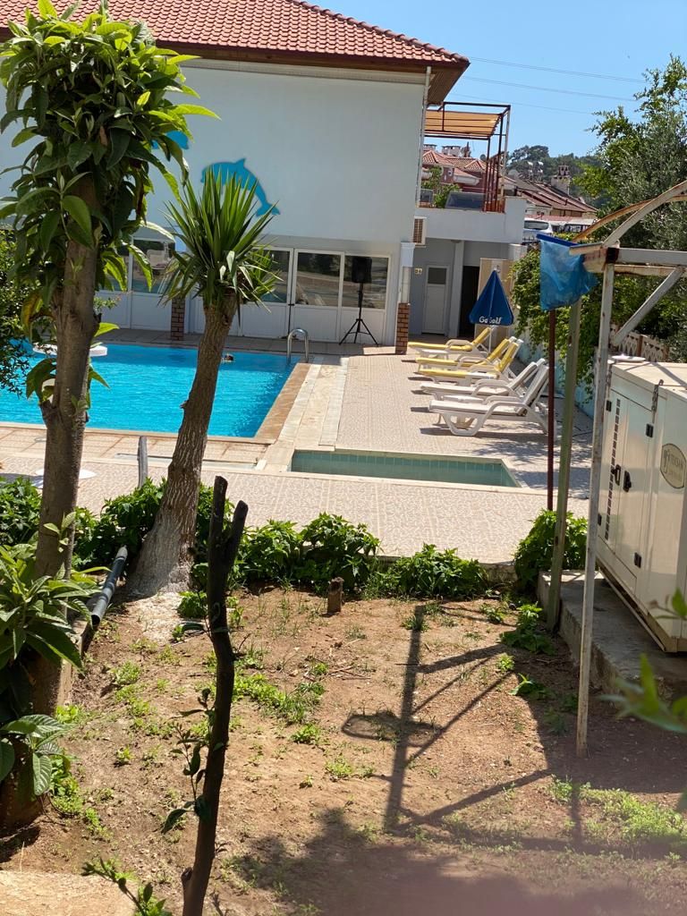 Una propiedad residencial con piscina, zona de estar cubierta al aire libre y jardín.