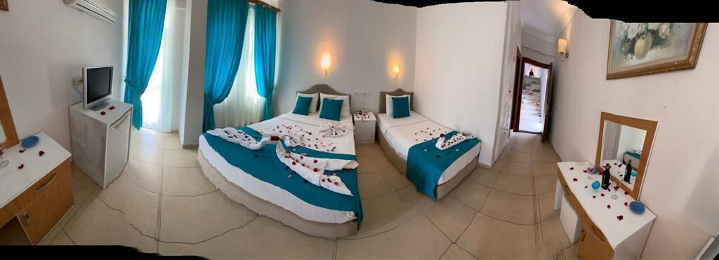 A hotel room with two beds, a desk, a TV, and a bathroom.