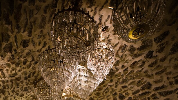 A bar with stone walls, multiple stools, and a variety of bottles and glasses. - Lida Mary (Chios)