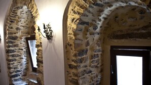 A stone corridor with a window and a wall-mounted light fixture. - Lida Mary (Chios)