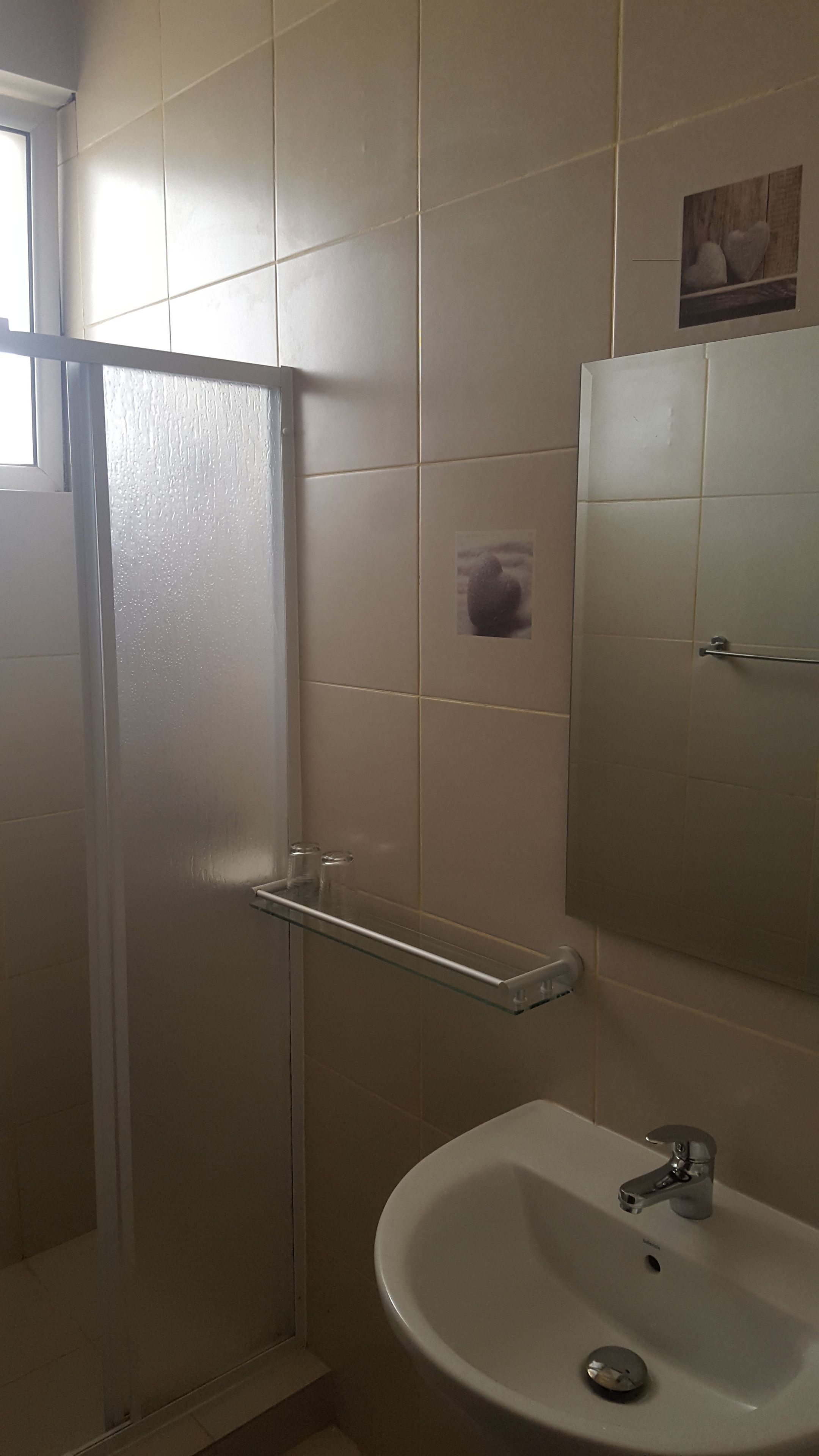 A bathroom with a glass shower enclosure, a white sink, and a mirror above the sink.