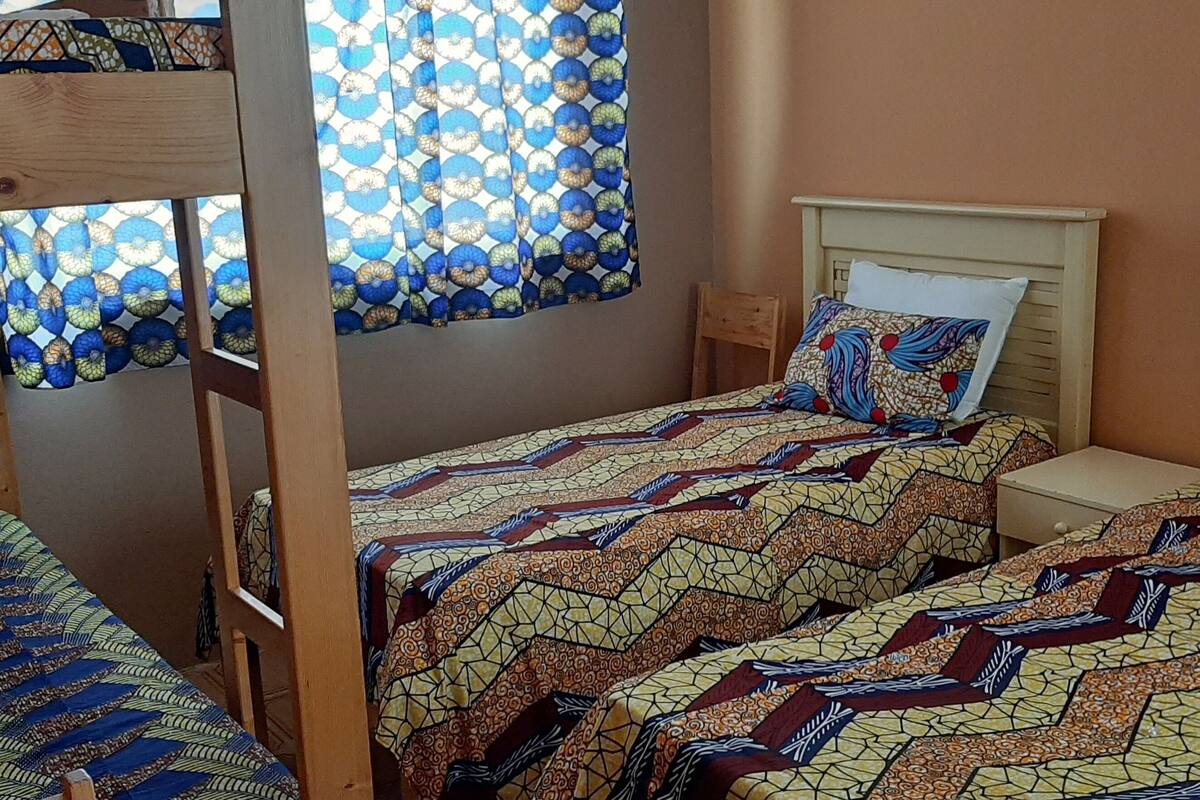 Ein Zimmer mit Etagenbetten, einem kleinen Nachttisch und einer Betttdecke mit Muster.