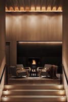 A modern living room with a fireplace, two sofas, and a staircase leading to an upper level.