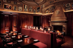 A dimly lit restaurant with wooden paneling, a fireplace, and framed pictures on the walls.