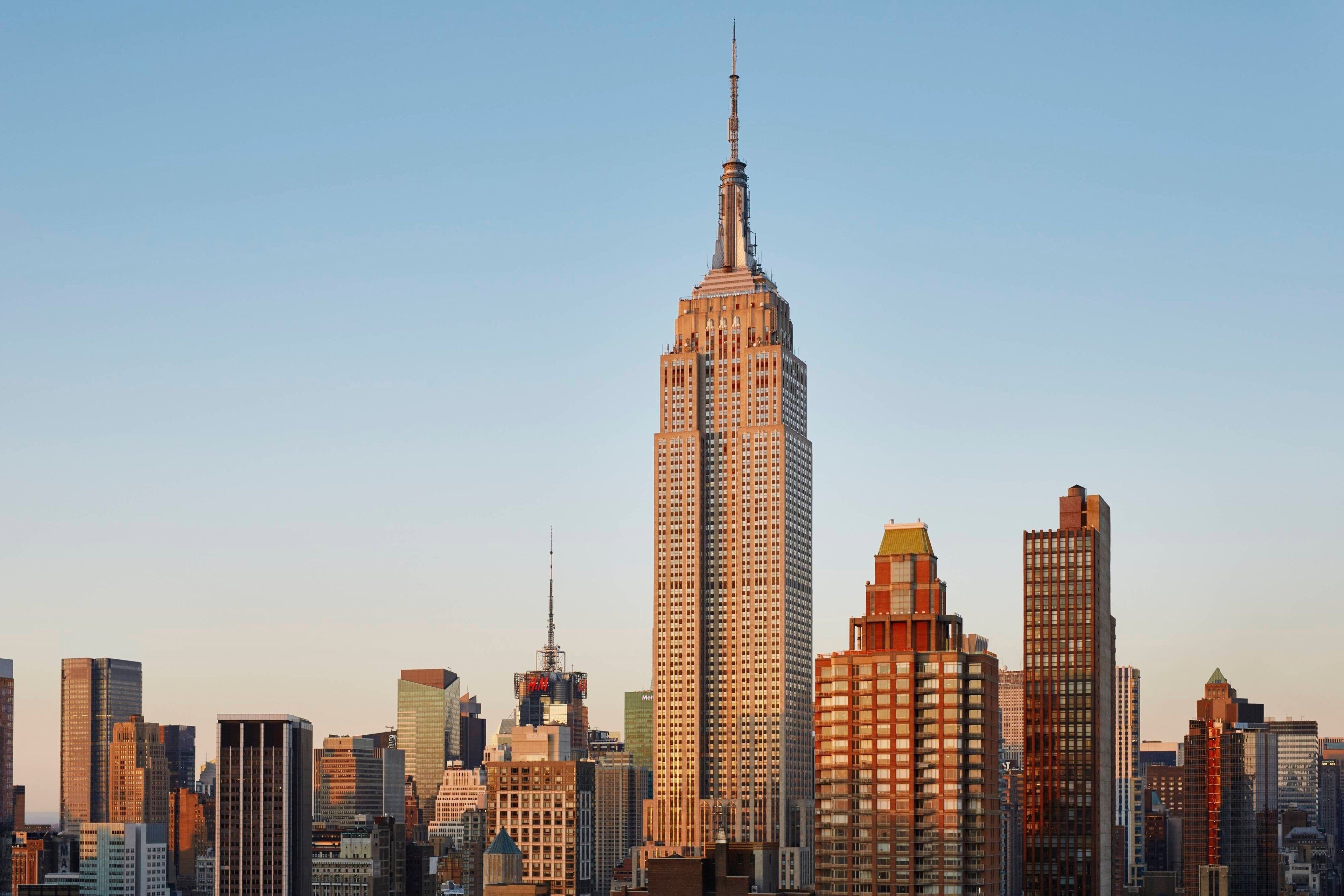 Paesaggio urbano con l'Empire State Building in posizione centrale, circondato da altri grattacieli.