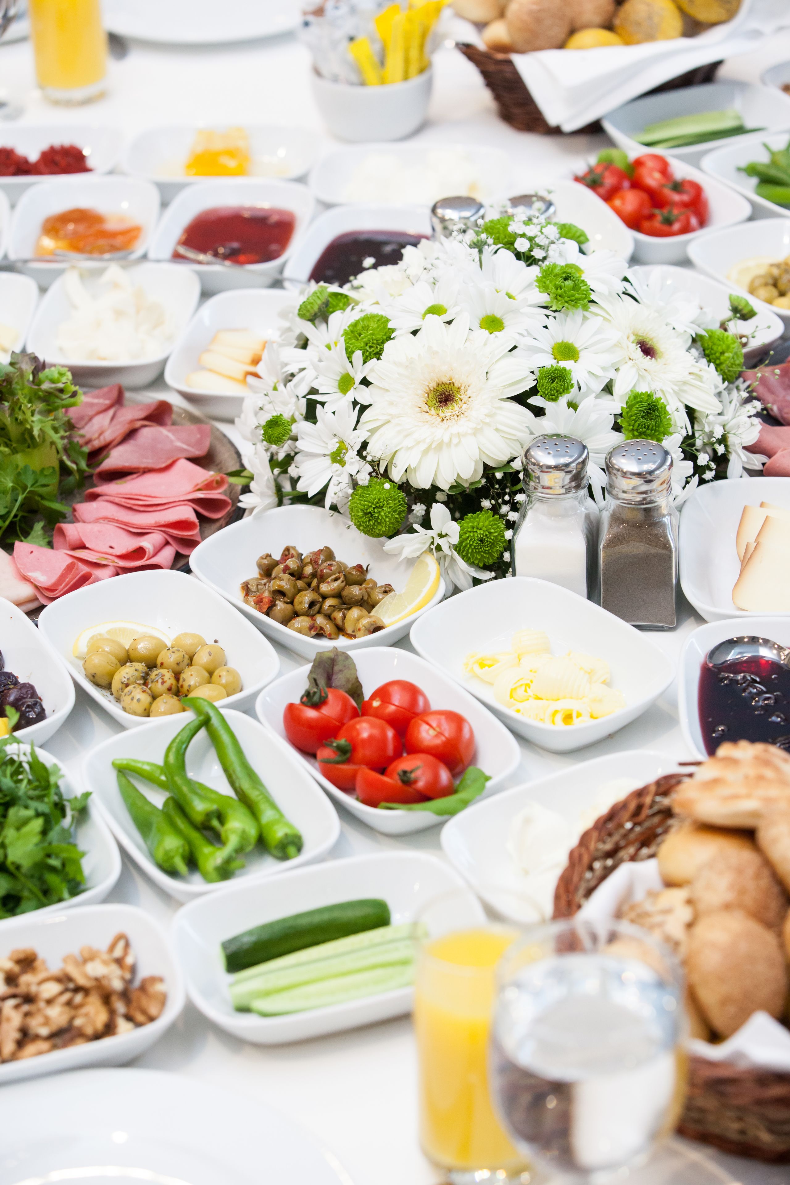 A table with various food items and condiments, including meats, cheeses, olives, and vegetables.