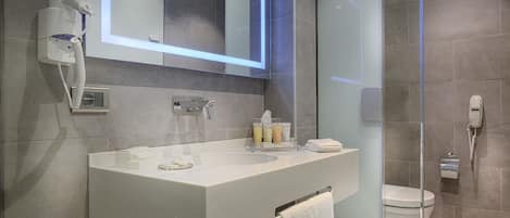 Un baño moderno con un lavamanos blanco, un espejo, un cabezal de ducha manual y un inodoro.