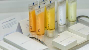 A display of TAV Airport Hotel products, including shampoo and body wash bottles, arranged on a table with white boxes.