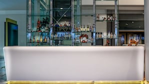 Zona de bar moderna con mostrador blanco y estantes llenos de botellas de licores.