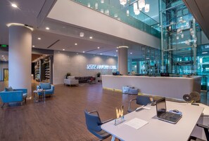 A modern hotel lobby with a reception desk, seating area, and a glass atrium. - Tav Airport Hotel Izmir (Izmir)