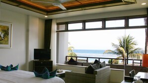 Una camera d'albergo con un letto, una televisione, un divano e un'ampia finestra vista mare.