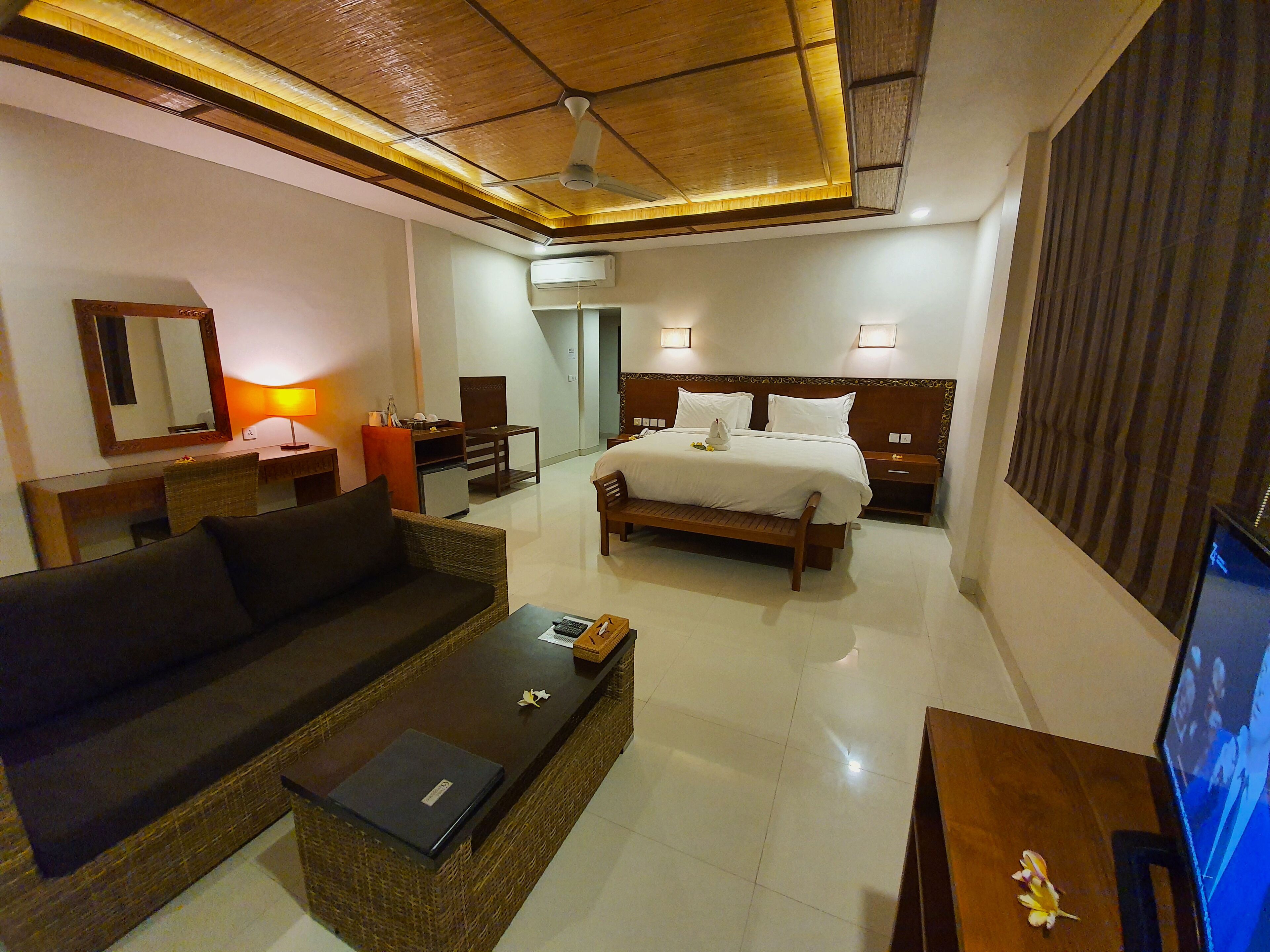 A hotel room with a bed, a sofa, a desk, and a television.