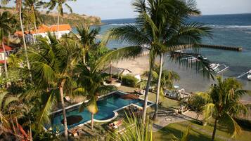 Un resort con piscina, palmeras y vista al océano.