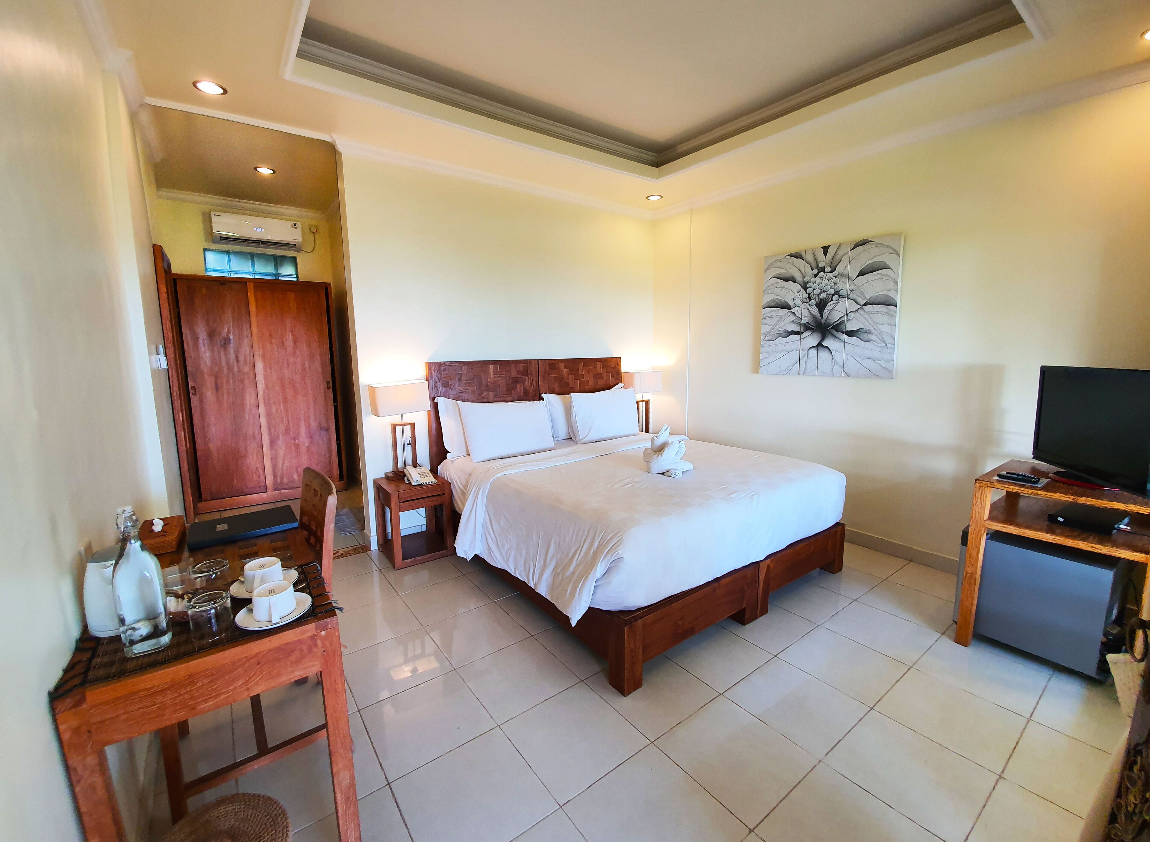 A hotel room with a bed, bedside table, lamp, and a television.