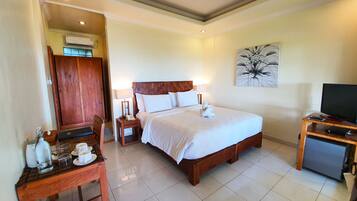 A hotel room with a bed, bedside table, lamp, and a television.
