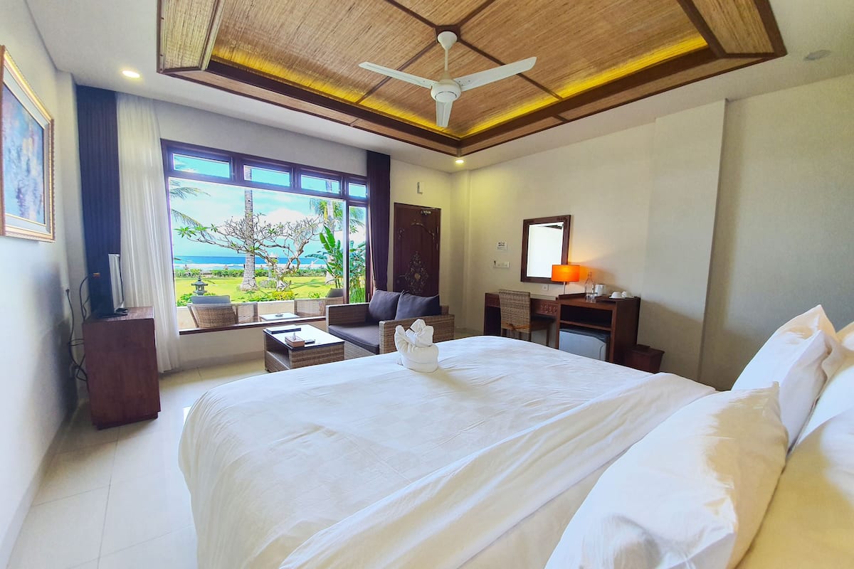 A hotel room with a large bed, a desk, a chair, and a view of the ocean.