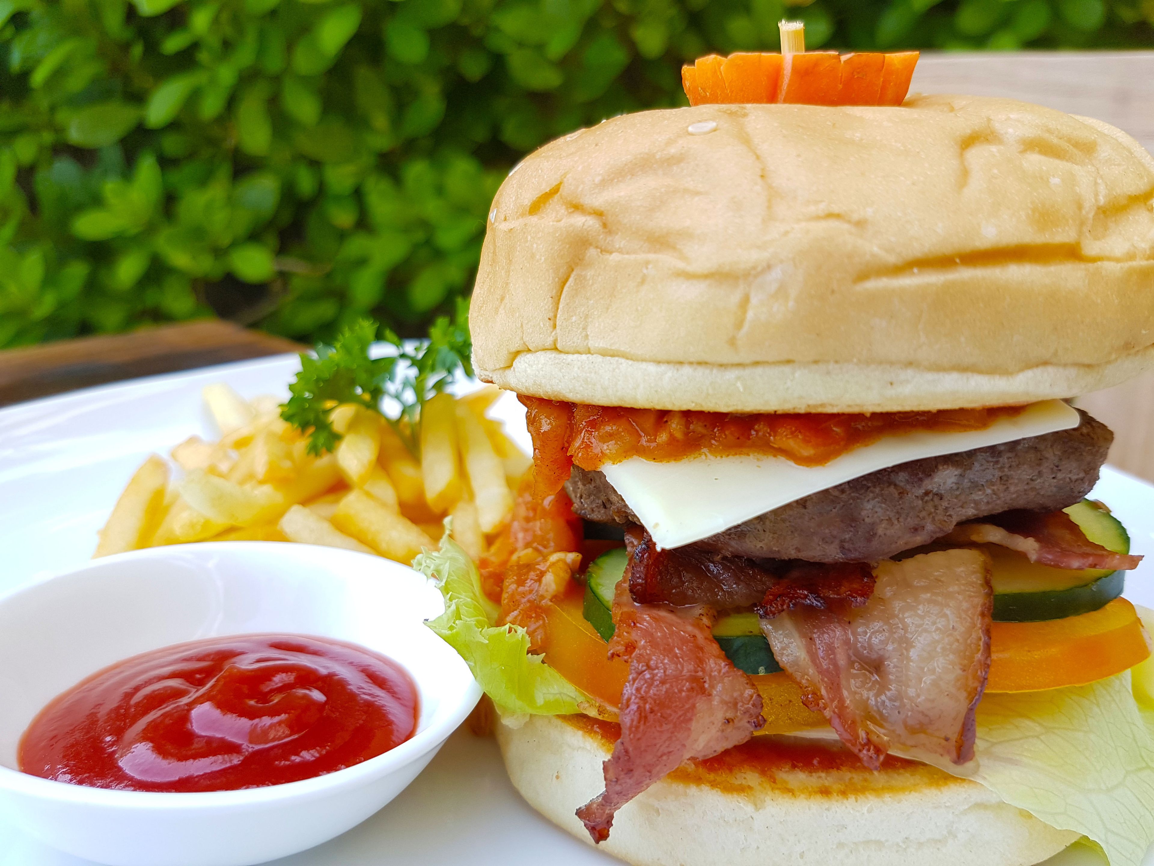 A burger with fries and ketchup on a white plate.