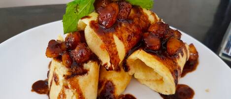 A plate of pancakes with syrup and a mint leaf garnish.