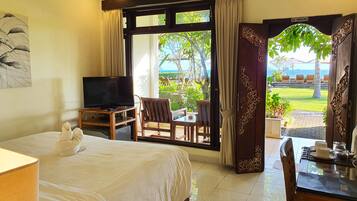 A hotel room with a bed, a TV, a desk with a chair, and a view of the outdoors.