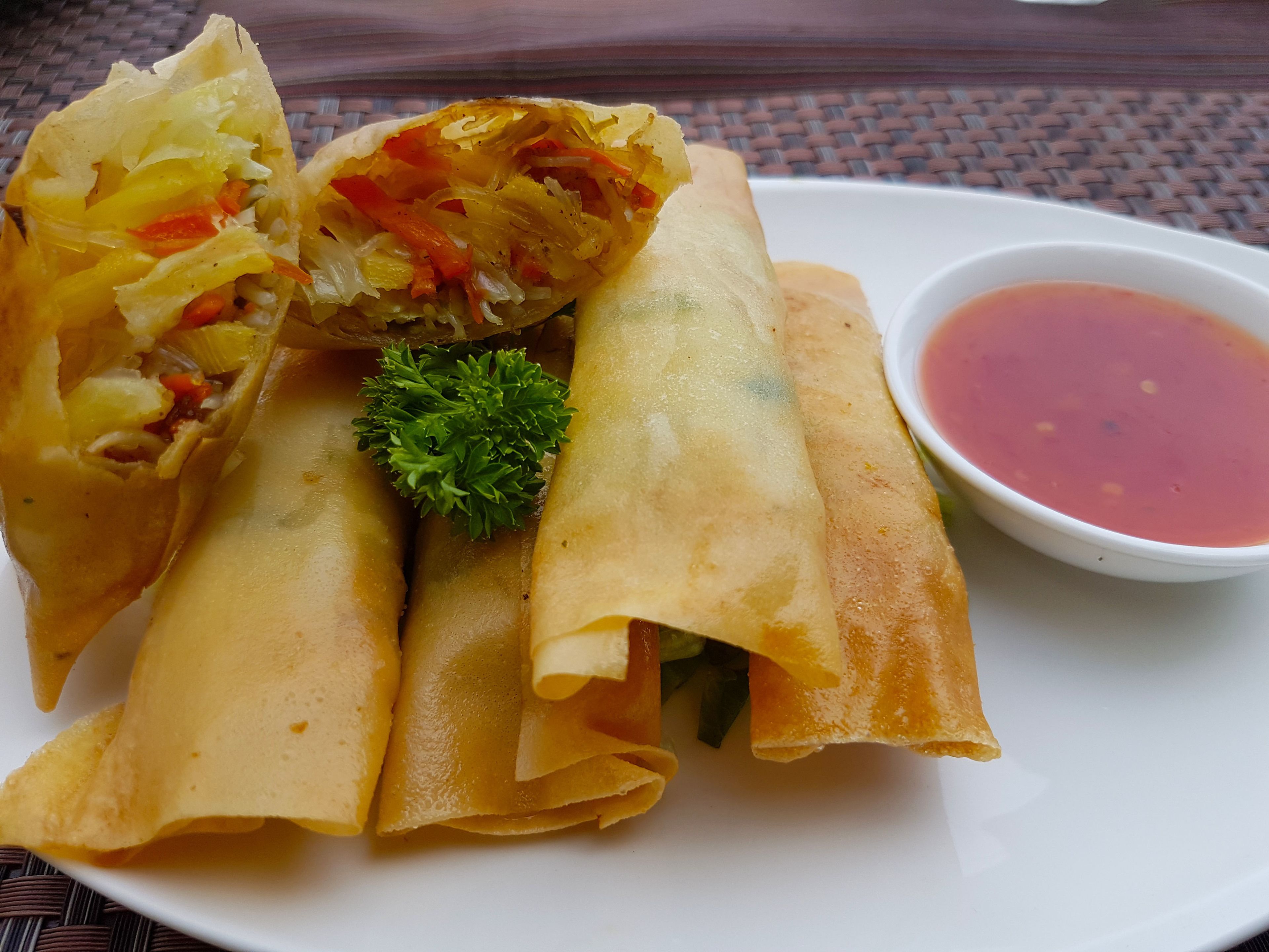 Un plato de rollitos primavera con salsa para mojar.